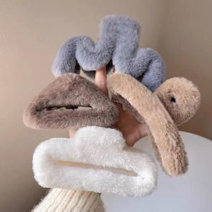 Detailed view of four plush faux fur hair claw clips in grey brown and white colors