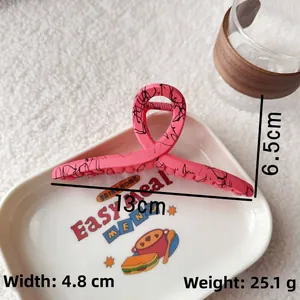 Pink large shark hair clip with marble pattern detail on a decorative ceramic plate