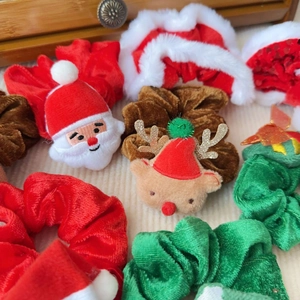 Weihnachts-Haargummis aus Samt mit Rentier- und Nikolausmotiven auf weichem Hintergrund