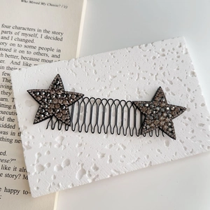 Dettaglio del pettine per capelli nero a onde con stelle decorate in strass lucidi