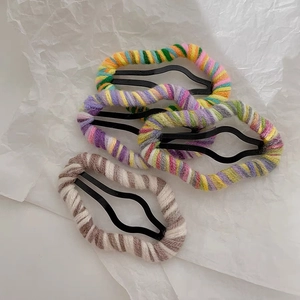 Detailed view of four colorful handmade knitted wool hair clips on a white textured paper