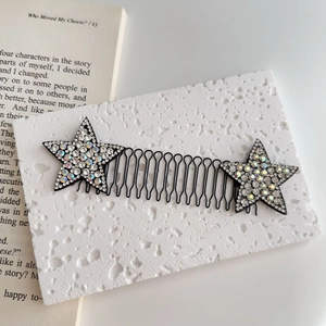 Dettaglio del pettine per capelli ondulato con stelle di strass su un libro aperto