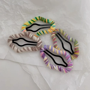 Close-up of four handmade knitted wool cloud hair clips in colorful pastel patterns