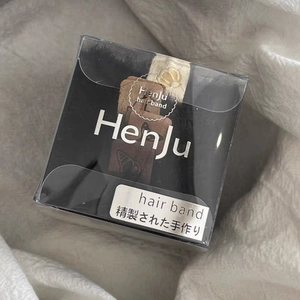 Gros plan d'un bandeau fait main dans son coffret cadeau noir de la marque Henju
