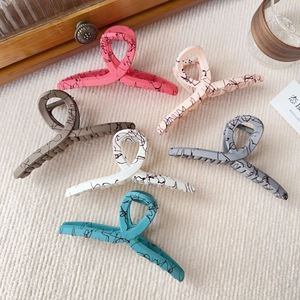Set of large matte hair claw clips in six assorted colors on a natural wooden tray