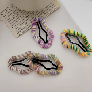 Detailed macro view of four colorful knitted wool wrap metal wavy hair clips on paper