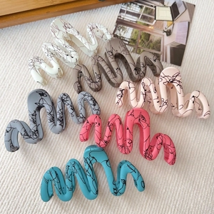 Detail showing wavy matte hair claws with marble texture in six assorted colors