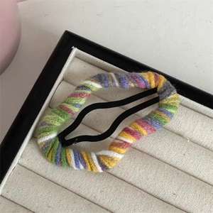 Close-up of a handmade knitted BB hair clip with colorful rainbow yarn stripes for girls