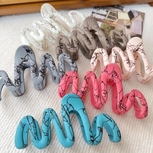 Detail of large matte wave hair claws with black artistic graffiti in six assorted colors