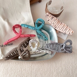 Detail view of six marble pattern hair claws in assorted colors on a silver tray