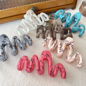 Assorted colorful matte claw clips with graffiti patterns shown on a soft fabric surface