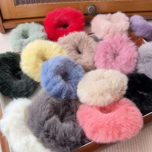 Detailed view of fluffy plush scrunchies in assorted colors on a white tray display