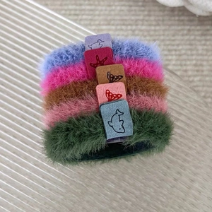 Détail de cinq chouchous en peluche colorés avec des étiquettes à motifs marins