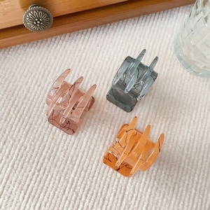 Detailed view of three matte hair claws with marble patterns in pink, grey and orange colors