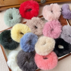 Detailed close-up of colorful plush scrunchies in a wooden tray with soft furry textures