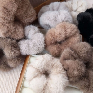 Detailed texture of assorted plush faux fur scrunchies in neutral autumn colors