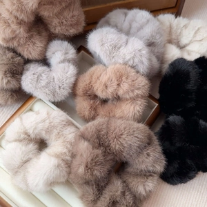Macro view of plush faux fur scrunchies in various colors on a wooden jewelry tray