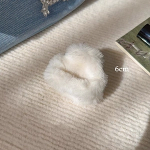 Detail shot of a 6cm white plush hair claw clip with soft texture on knit fabric