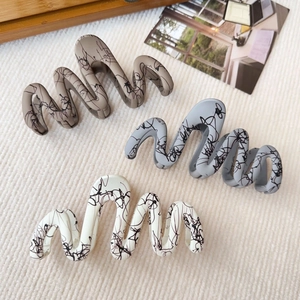 Detailed view of matte hair claws with black graffiti lines in brown, gray, and cream