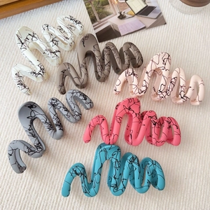 Close-up of wavy shark hair claws in six colors with ink splatter matte texture