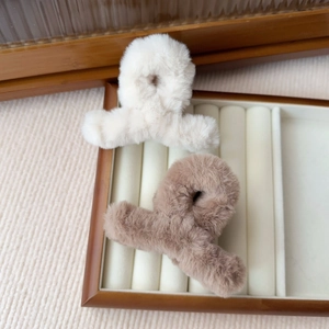 Dettaglio di piccole mollette per capelli in peluche crema e marrone chiaro con pelliccia