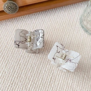 Detail view of small marble pattern hair claws in grey and white with metal springs