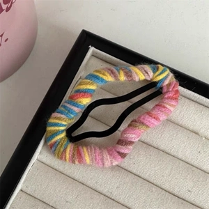 Detail of colorful knitted yarn wrapped around a metal BB hair clip in a jewelry box