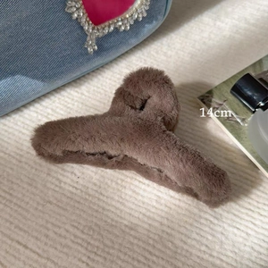 Detail view of a 14cm large brown plush hair claw clip on a stylish textured background