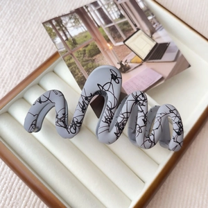 Macro detail of large grey wavy hair claw with black abstract marble ink textures