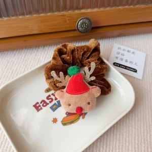 Detail eines braunen Weihnachts-Haargummis aus Samt mit Rentier-Plüsch und roter Mütze