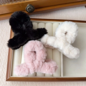 Dettaglio di fermacelli per capelli in peluche nei colori nero, beige e rosa