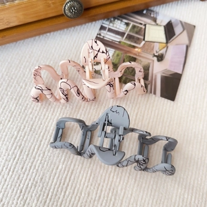 Detail of pink and gray hair claw clips with ink splash texture on knit fabric