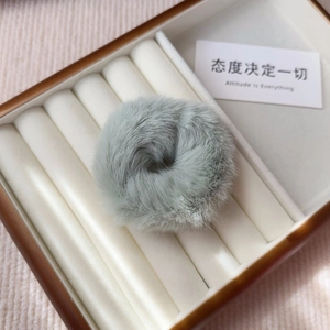 Detail of light gray fluffy plush hair tie accessory in a jewelry display box