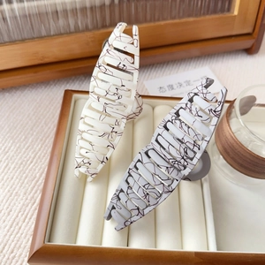 Set of two marble textured shark hair clips in cream and grey on a wooden tray