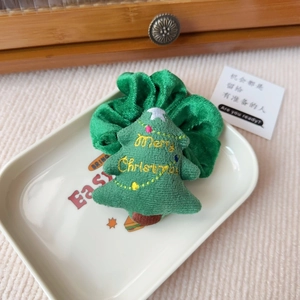 Detail eines grünen Samt-Weihnachtshaargummis mit Stickerei auf einer Keramikplatte