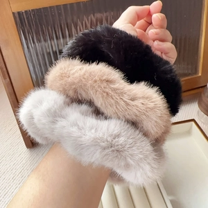 Three-piece faux mink fur scrunchies in black, camel and grey colors worn on wrist