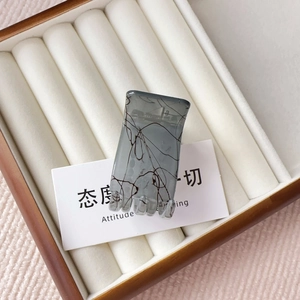 Detail view of a grey marble pattern rectangular hair claw clip on a white display tray