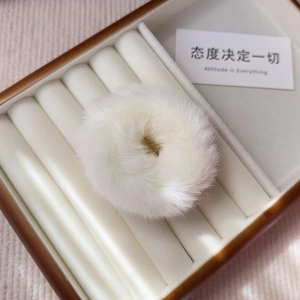 Macro shot of fluffy white faux fur hair tie showing soft texture in jewelry display box
