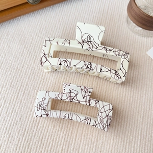 Set di due mollette per capelli beige con motivo nero in diverse misure su maglia