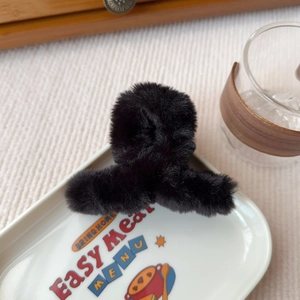 Dettaglio della consistenza della molletta per capelli in peluche nero su un piatto decorato