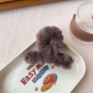 Primo piano di una pinza per capelli in peluche grigio con morbida pelliccia sintetica