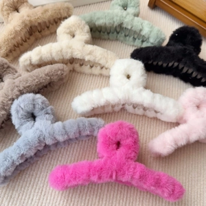 Flache Darstellung von bunten Plüsch-Haarklammern in Beige, Rosa und Grau auf Streifenstoff