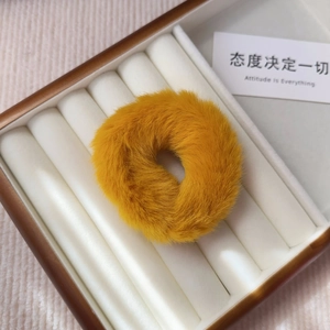 Close-up of a fluffy ginger faux fur scrunchie presented in a white velvet jewelry display box