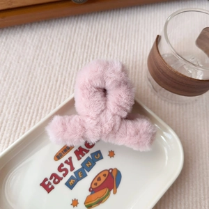 Dettaglio della molletta per capelli in peluche rosa su vassoio in ceramica elegante