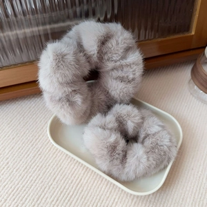 Detailed view of grey-brown plush faux mink hair scrunchies on a ceramic tray