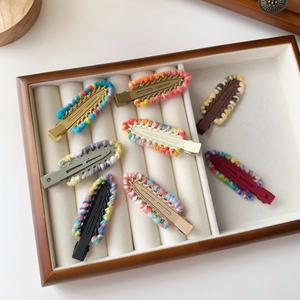 Set of eight colorful knitted yarn hair clips with matte metal base in a wooden tray