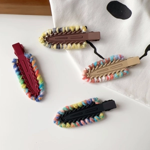 Detail view of four contrast color knitted yarn hair clips on a clean white background