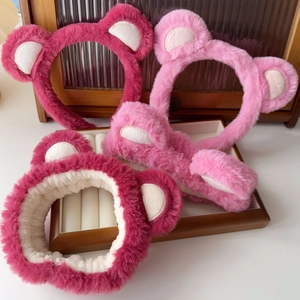 Close-up of pink coral fleece bear ear headbands and matching plush hair ties on tray