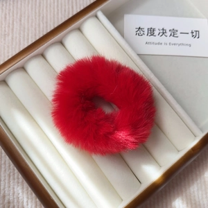 Detail of a fluffy red faux fur hair scrunchie inside a classic brown and white jewelry box