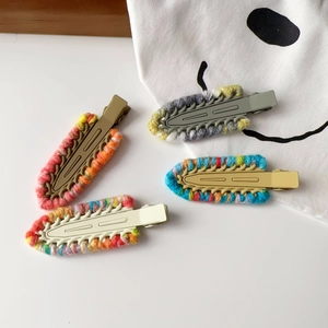 Detail view of four colorful handmade crochet hair clips with matte metal duckbill base